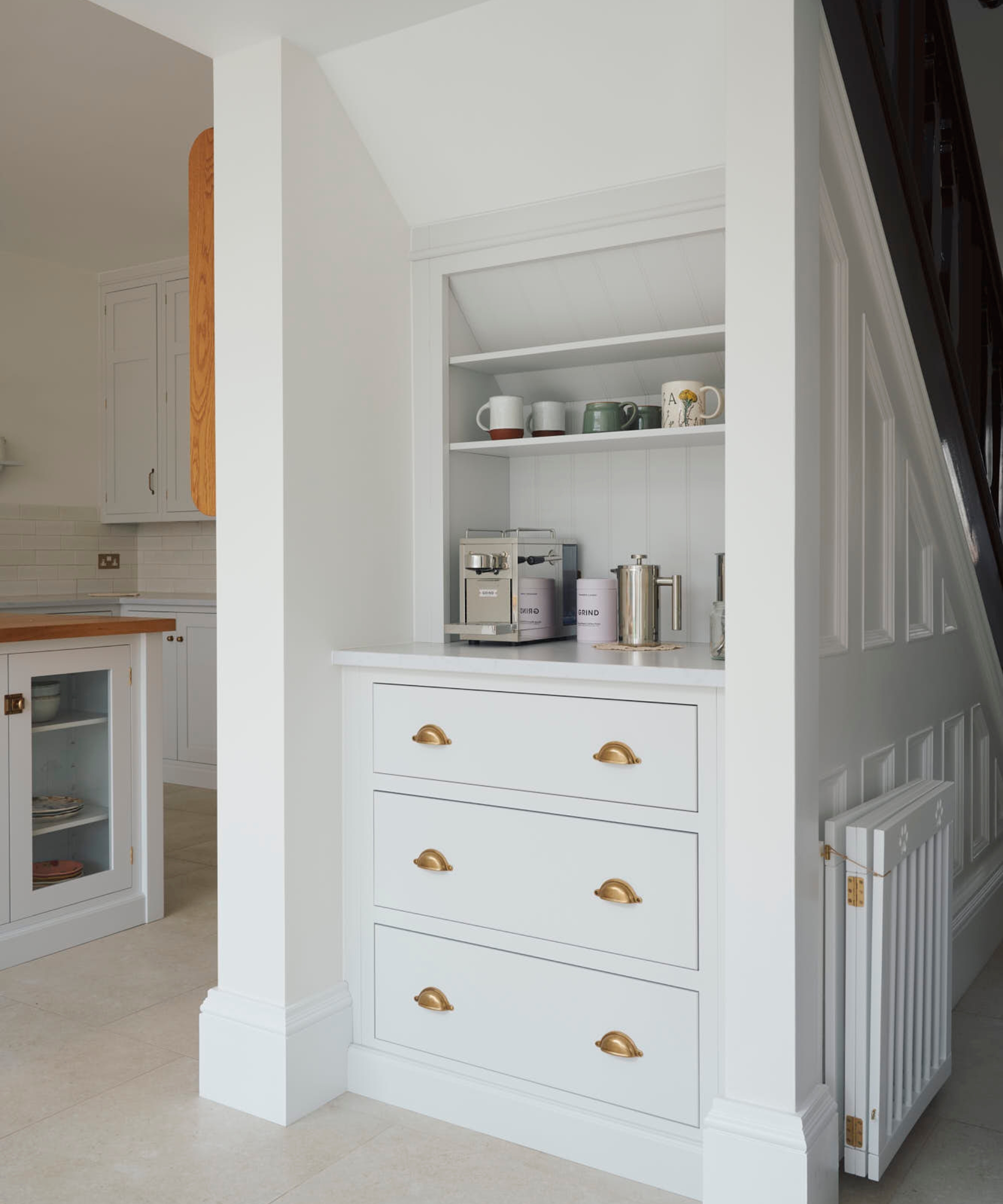 A white open pantry cabinet installed beneath a staircase