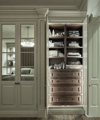 inside of fitted wardrobe showing wooden doors, open shelving and internal lighting