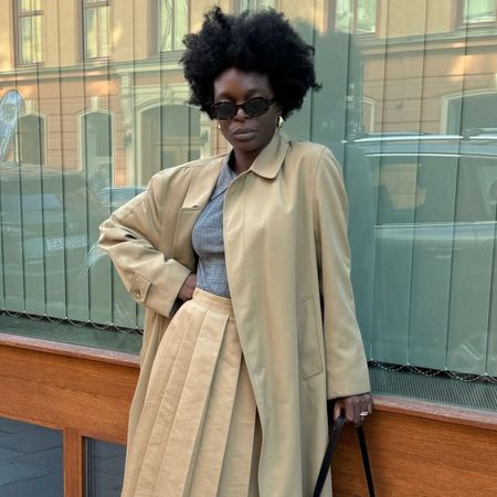 Influencer wears a pleated miniskirt in beige with a matching trench coat.