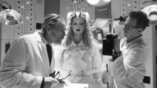 From left to right: Ethan Hawke holding his glasses in his hands and looking to his right, Taylor Swift standing next to him with an apperatus on her head and Josh Charles holding a pole to her head and holding up what looks like a radio with his left hand. 