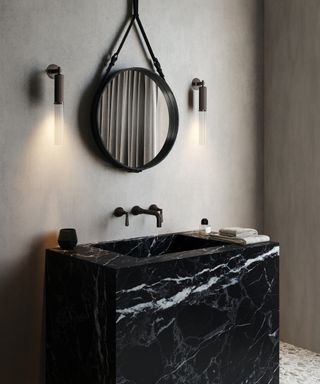 black and white veined marble washstand with black mirror above and wall lights