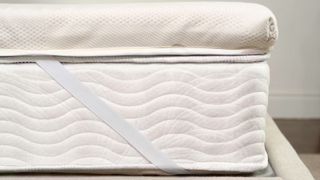 The Saatva Micro-Coil Hybrid Mattress Topper in al light bedroom