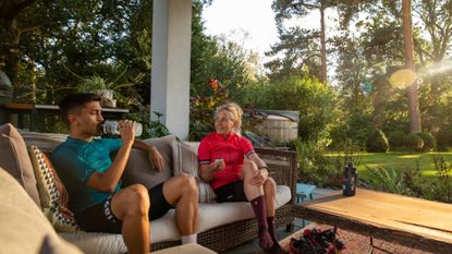 Male and female cyclist sitting down on the sofa post bike ride