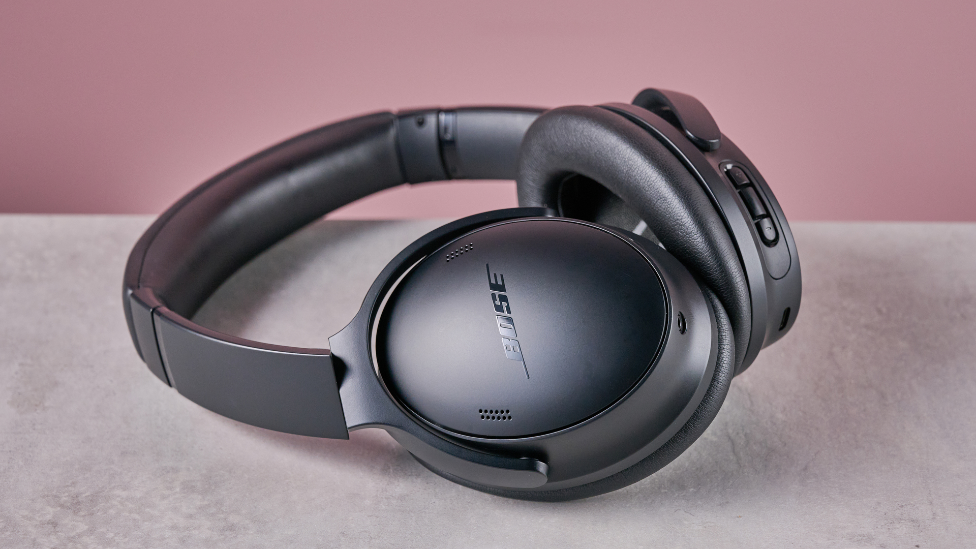 Bose QuietComfort Headphones on a gray surface with a pink background
