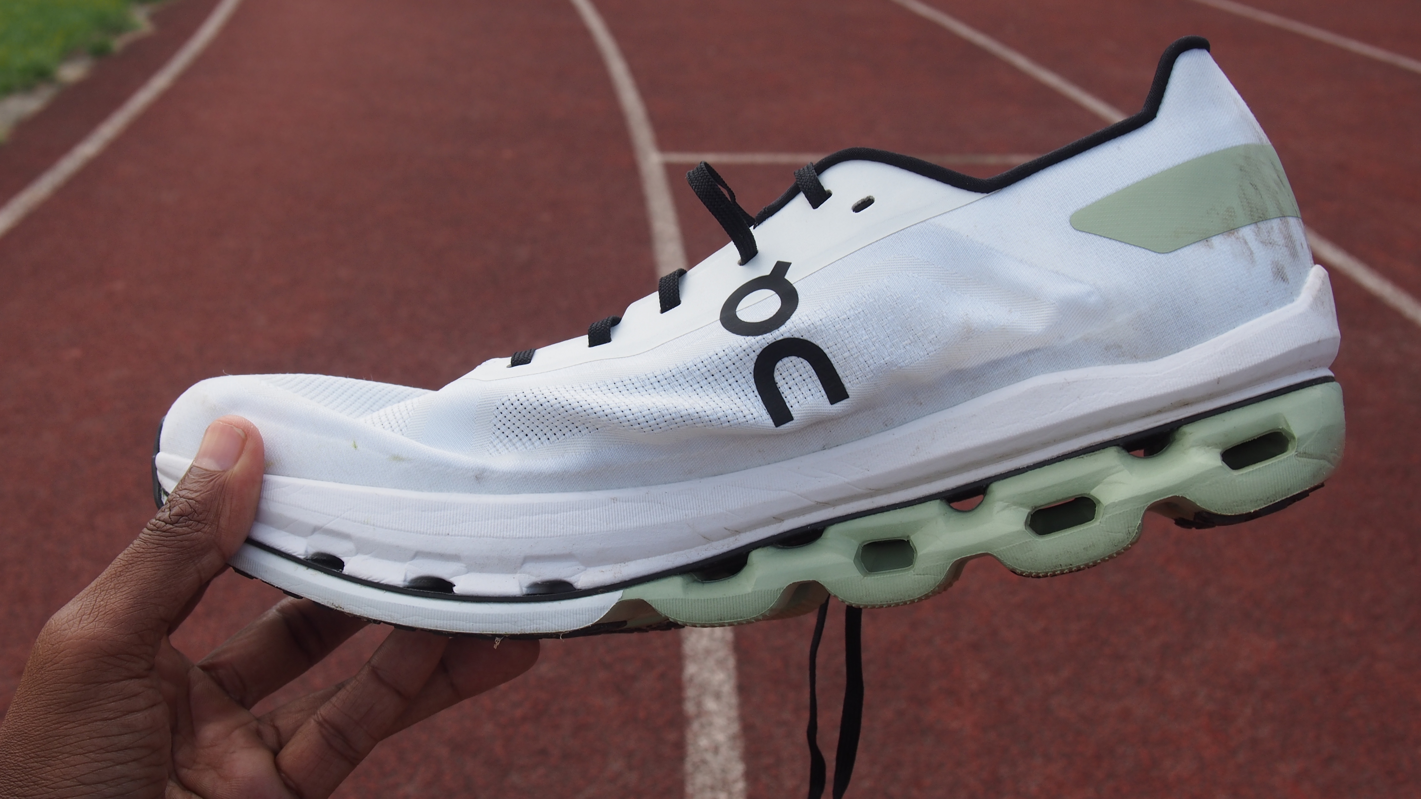 Man's hand holding a On Cloudboom Echo running shoe, showing the side profile
