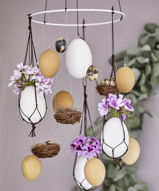 Beautiful DIY ceiling mobile with hen and quail's eggs, rustic nests, fresh geraniums, and macrame holders.