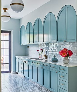 kitchen with aqua blue arched kitchen cabinets, white globe ceiling lights, white backsplash and patterned tile floor