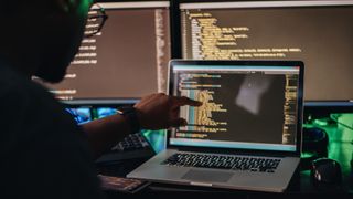 Man pointing at a screen with code on it.