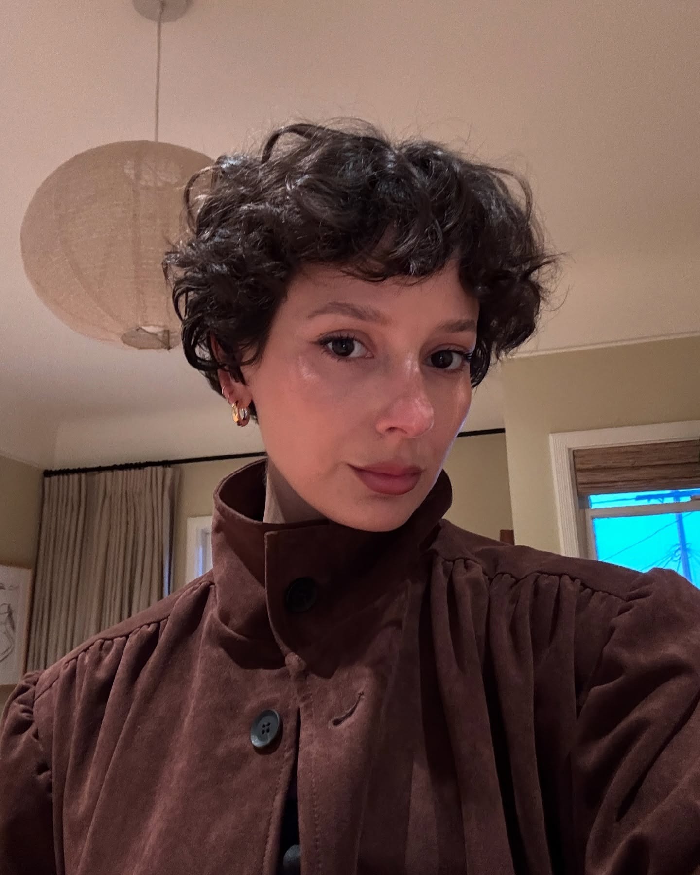 A woman with short hair and a brown jacket