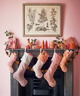 Christmas mantel decor ideas in a pink room with pink and orange decoration, and pink Christmas stockings