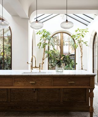 kitchen with roof light, arched patio doors, wooden island with marble top, sink inlaid and glass pendant lights above