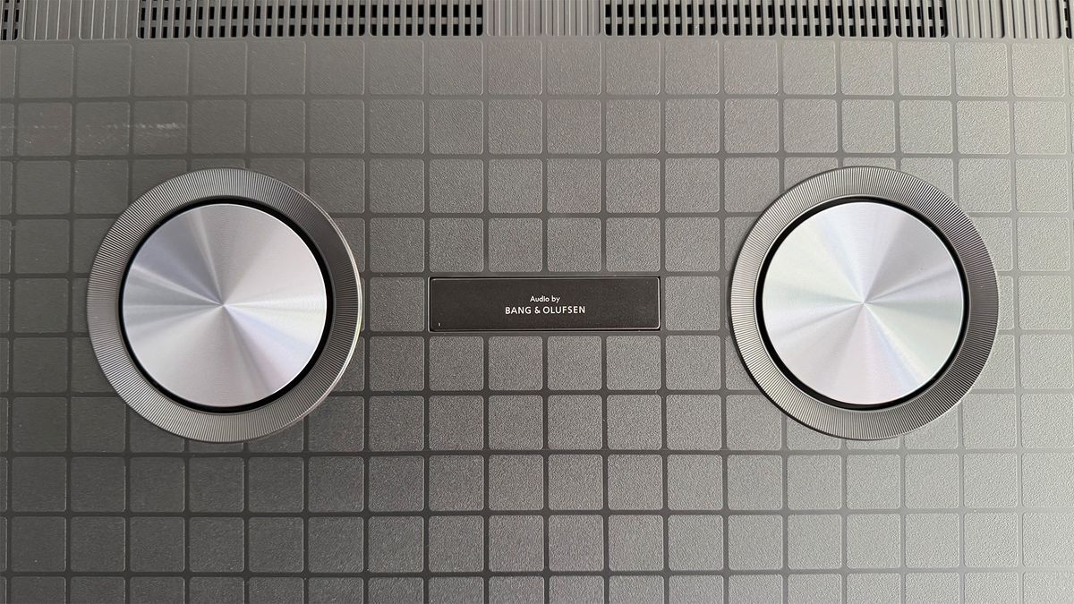 A close-up of two circular Bang &amp; Olufsen speakers on the back of the TCL 98C7K 98-inch TV.
