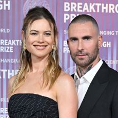 Behati Prinsloo and Adam Levine in front of purple backdrop