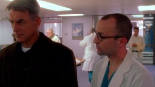 Jim Rash in a doctor's coat, talking to Mark Harmon in NCIS