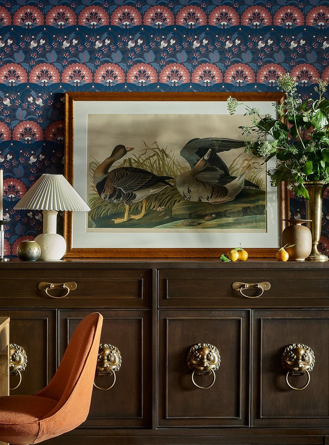 A dining room with lemons and fresh flowers placed atop the console