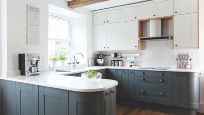 U-shaped kitchen with two-tone cupboards, white worktop and rounded peninsula