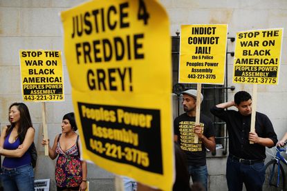 Demonstrators hold up signs outside the Freddie Gray hearing in Baltimore