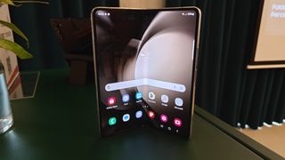 Samsung Galaxy Z Fold 5 står halvt öppnad på ett mörkt bord.