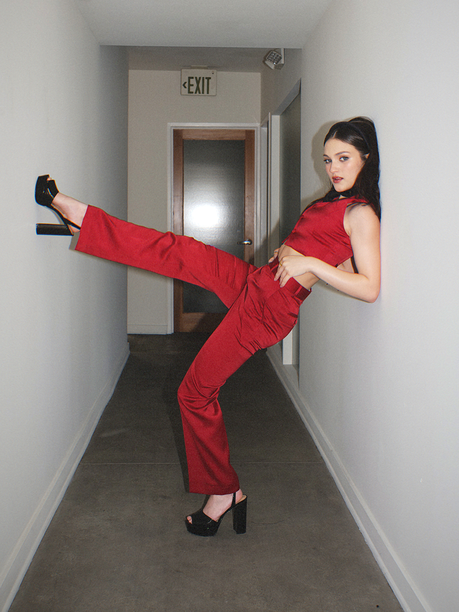 Izzy G. wears matching satin red top and pants with platform heels.