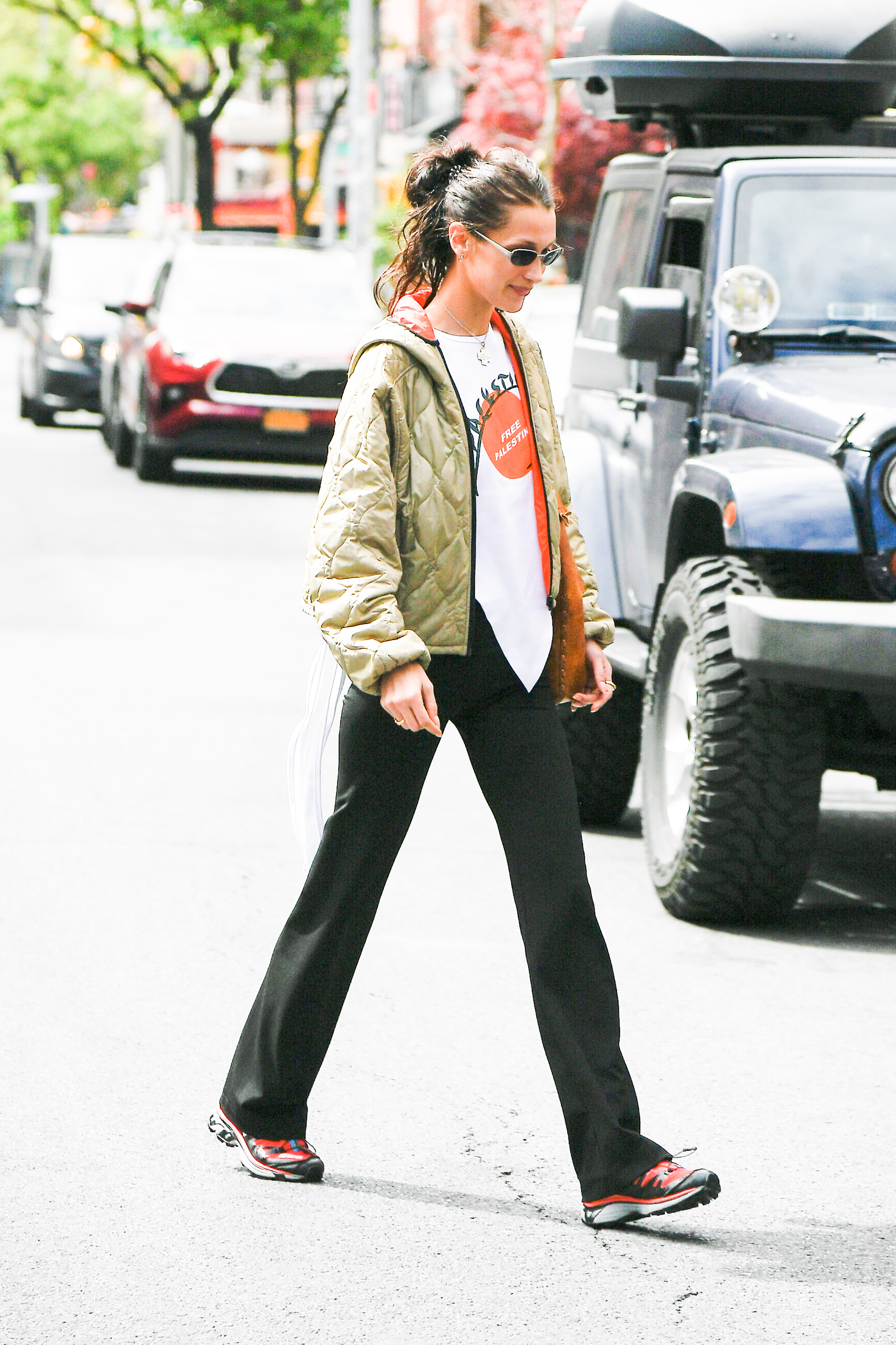 Bella hadid wearing black trousers, a sage green jacket, and black trousers in New York.