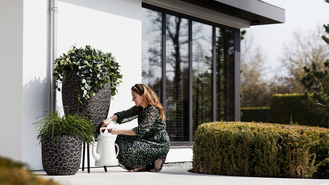 planted water butt with woman filling watering can