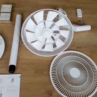The white Duux Whisper Flex Ultimate Fan being assembled on a wooden floor