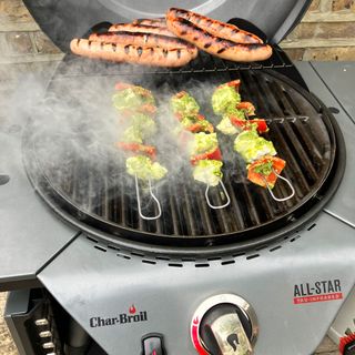 a close up of a barbecue grill with kebab skewers and hot dogs