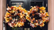 Two full foliage fall wreaths displayed on a black townhouse door in NYC