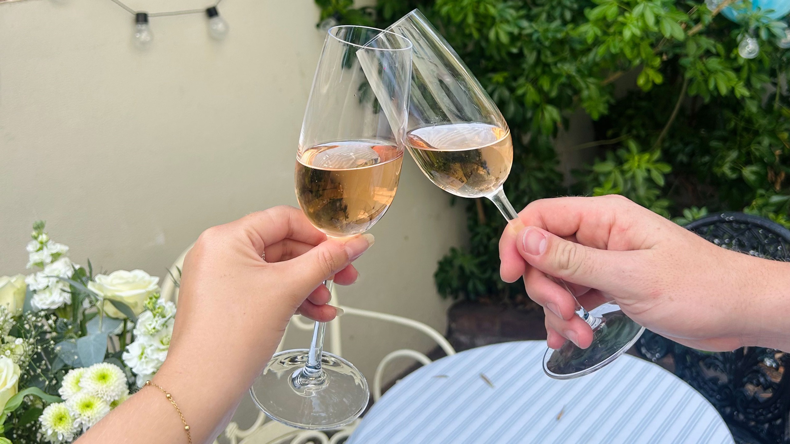 Two hands holding flutes of ros&amp;eacute; wine toasting