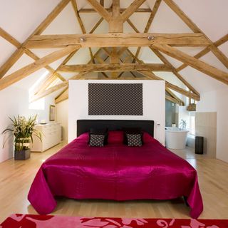 double bed with red satin cover in a large room