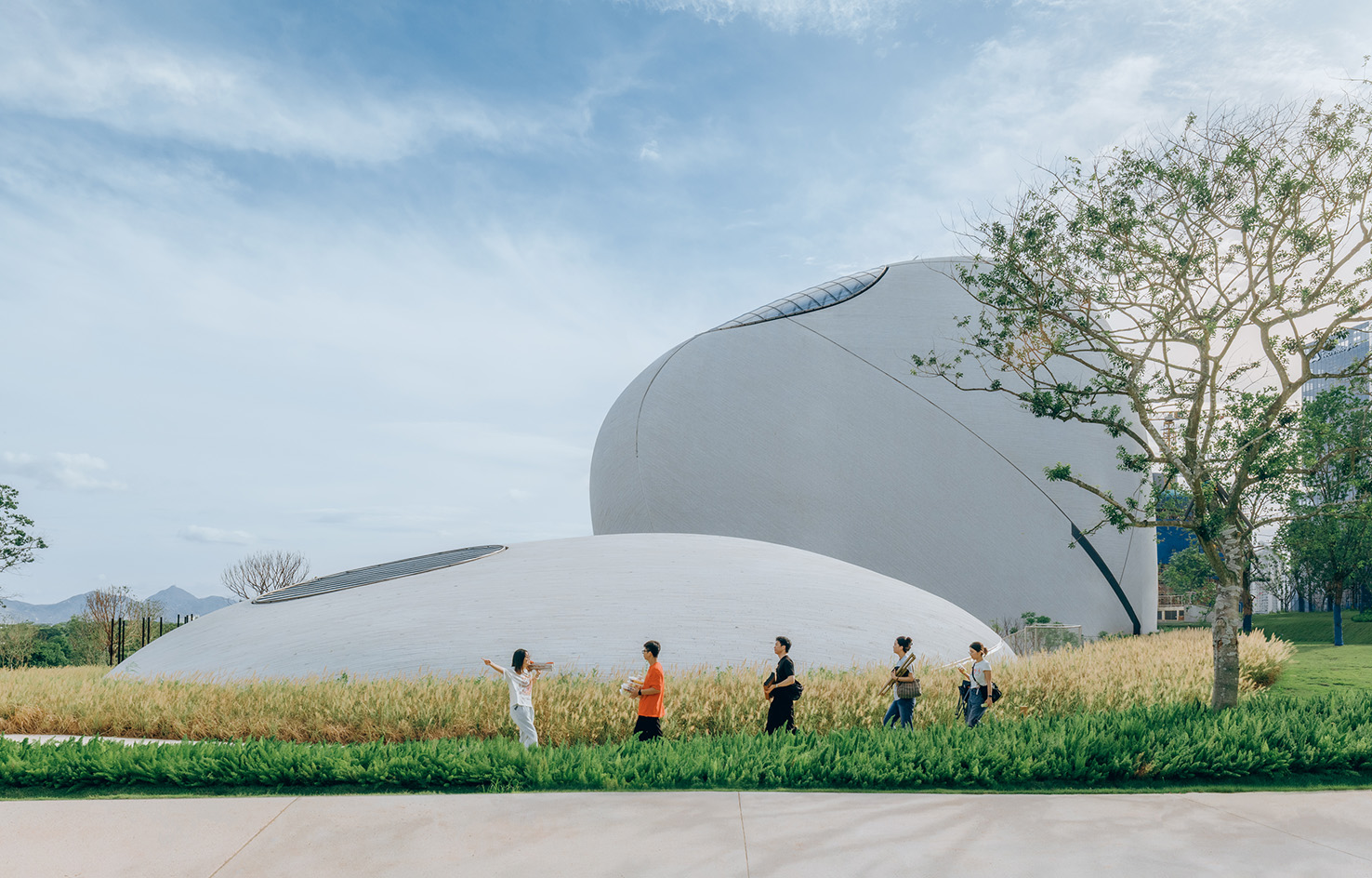 view of MAD Shenzhen Bay Culture Square, all white volumes and curves in a green park