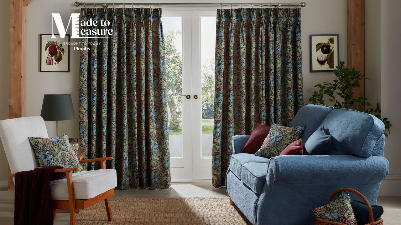 Living room with white armchair, blue sofa and botanical patterned curtains