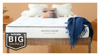 The Avocado Green Latex Mattress in off-white shown on a wooden bed frame and dressed with a blue bed throw