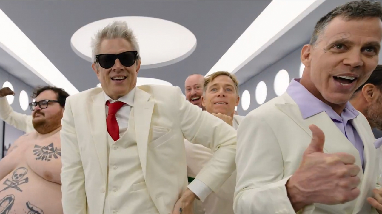 Johnny Knoxville and Steve-O in white suits with a shirtless Preston Lacy all looking at the camera