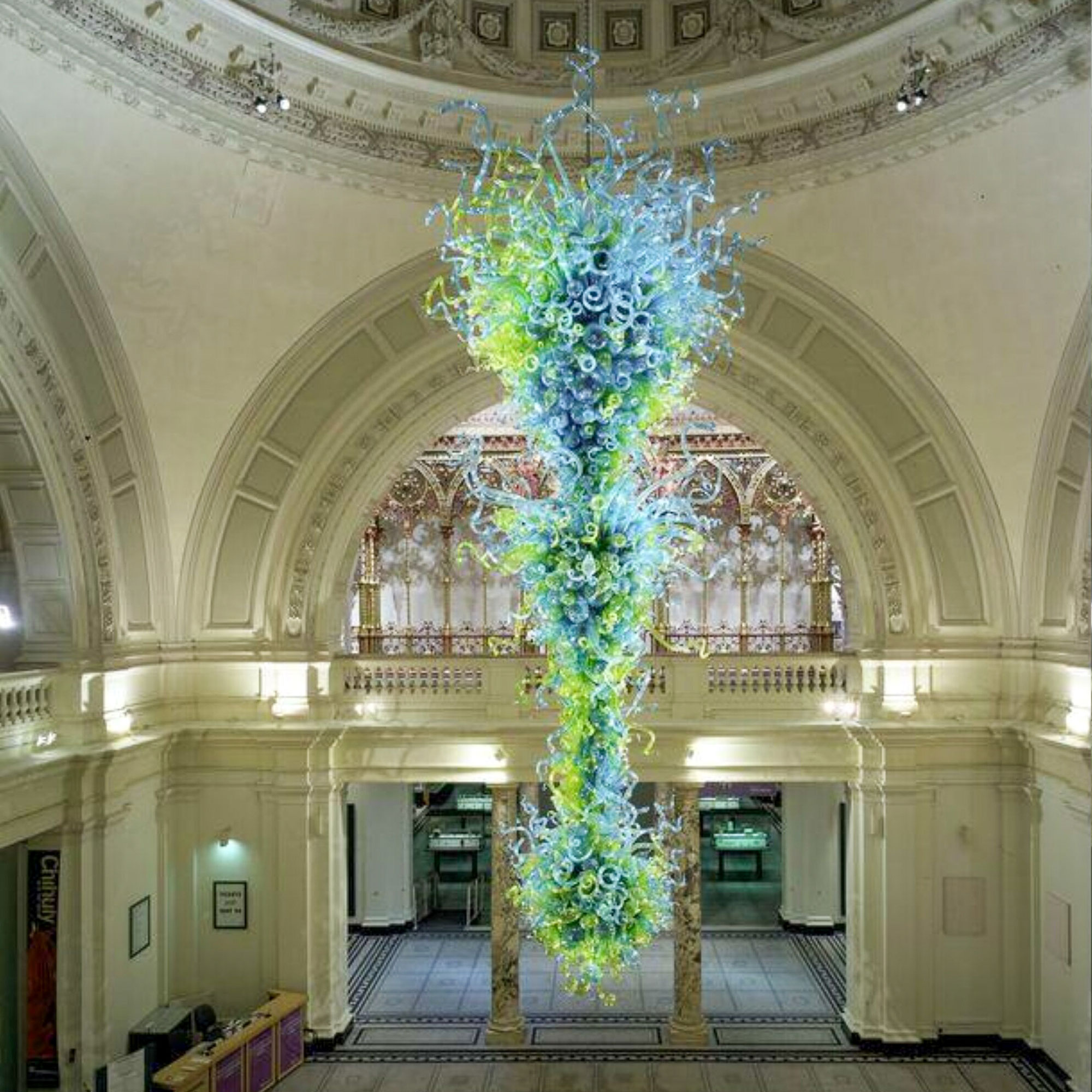 Elaborate green and blue glass chandelier hanging in V&amp;amp;A entrance hall