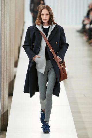 model wears gray leggings, navy peacoat, hoodie, crewneck, and a tee in Miu Miu Fall 2023