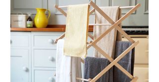Drying rack with towels drying in front of a cream AGA in a kitchen
