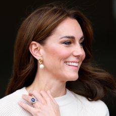 Kate Middleton holding her engagement ring up against her beige sweater