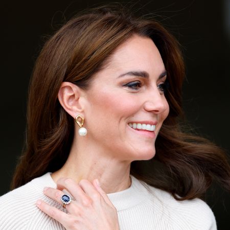 Kate Middleton holding her engagement ring up against her beige sweater 