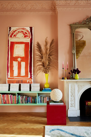 living room with pink walls, white fireplace and blue console with books