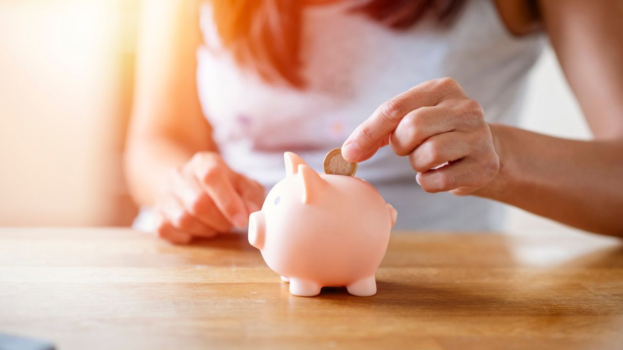 Woman putting money into piggy bank