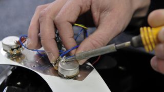 Man soldering guitar pots