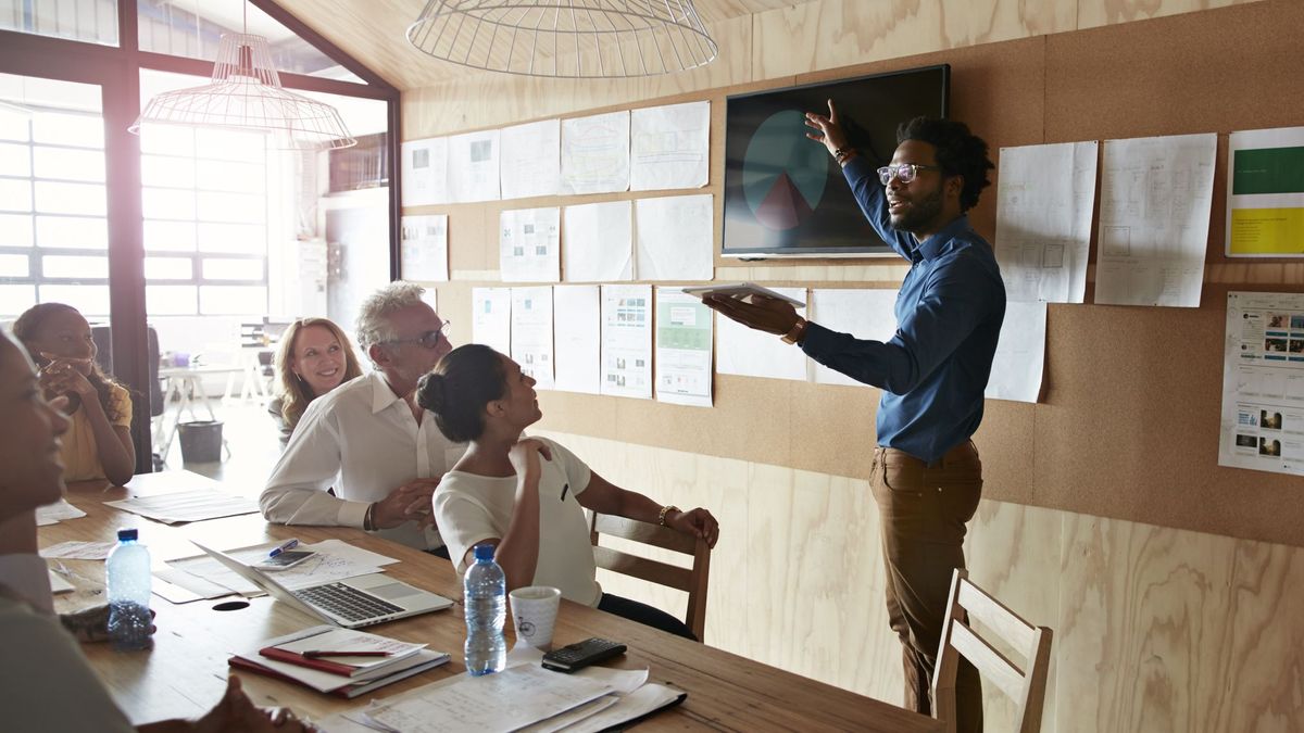 A person giving a presentation using a tablet and screen in a meeting room