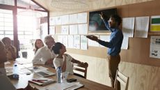 A person giving a presentation using a tablet and screen in a meeting room