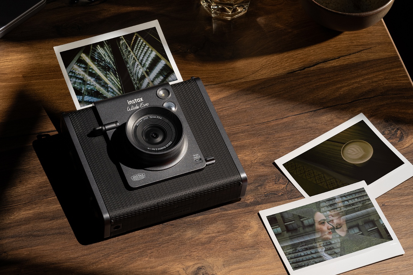 Fujifilm Instax Wide Evo instant camera on a wooden table with print coming out of its top