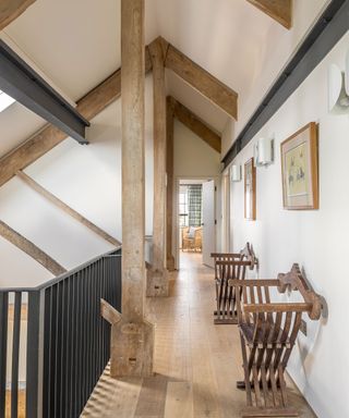 Landing with vertical and ceiling beams and wood floor with two chairs