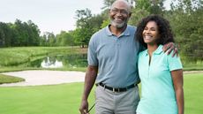 Smiling senior couple walking on golf course