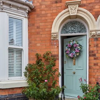 spring wreath hanging on a sage green front door of a Victorian terrace with