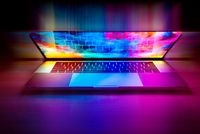 A half opened laptop with bright, multicolored light shining out of it.