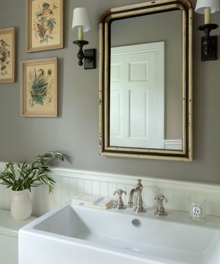 Stone colored walls, artwork on left of mirror, wall lights, vintage mirror, rectangular basin